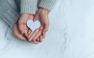 paper heart put in couple's hands on marble table