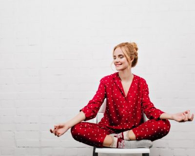 pleased-girl-red-pajamas-doing-yoga-white-wall-indoor-portrait-blonde-young-lady-sitting-lotus-pose-chair_197531-21744